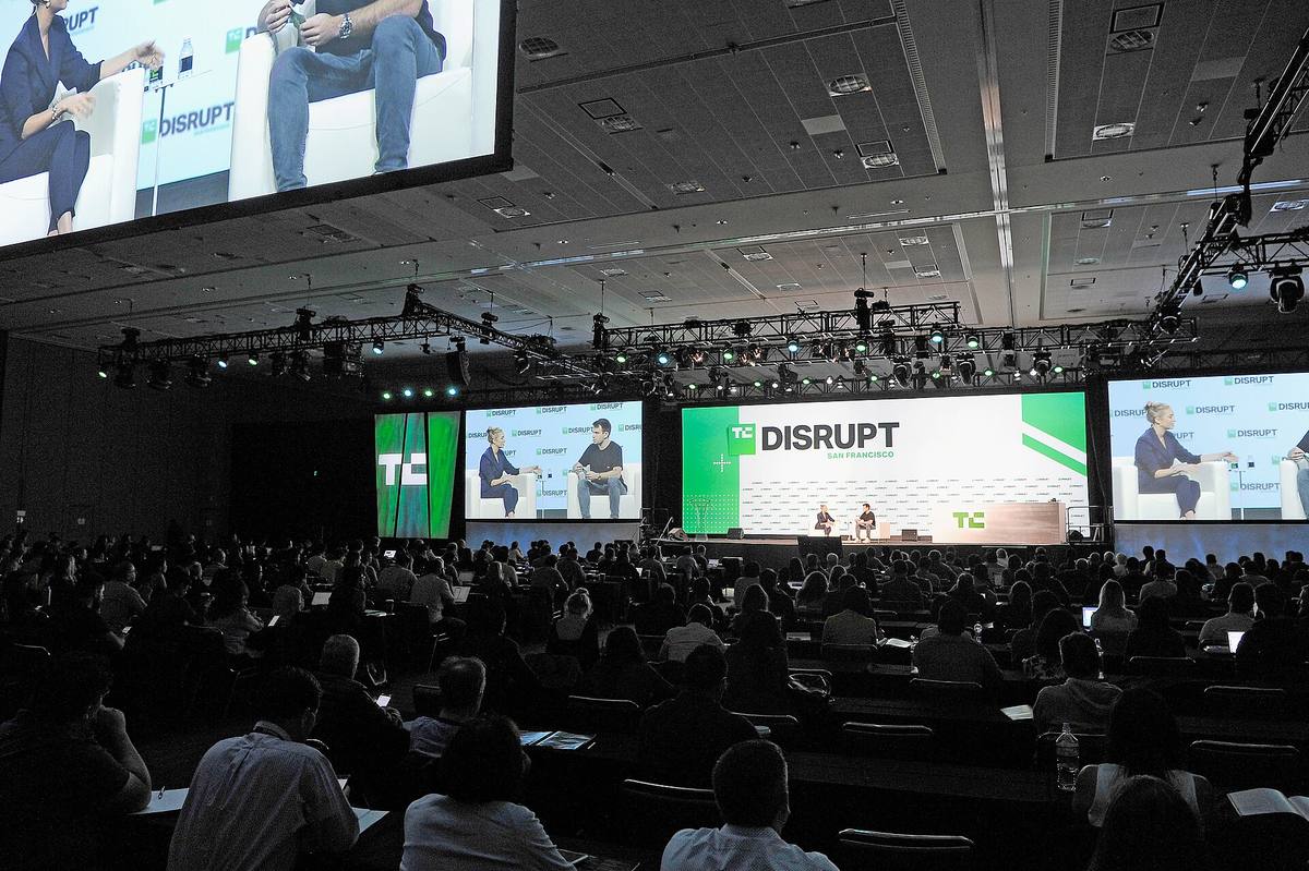 Whitney Wolfe Herd a moderátor na pódiu konference TechCrunch Disrupt před zaplněným sálem