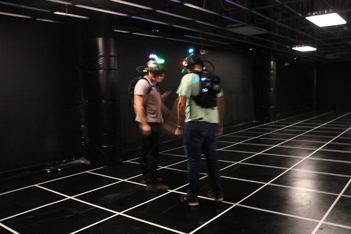 Dva hráči s brýlemi pro virtuální realitu a batohy s počítačem ve VR aréně