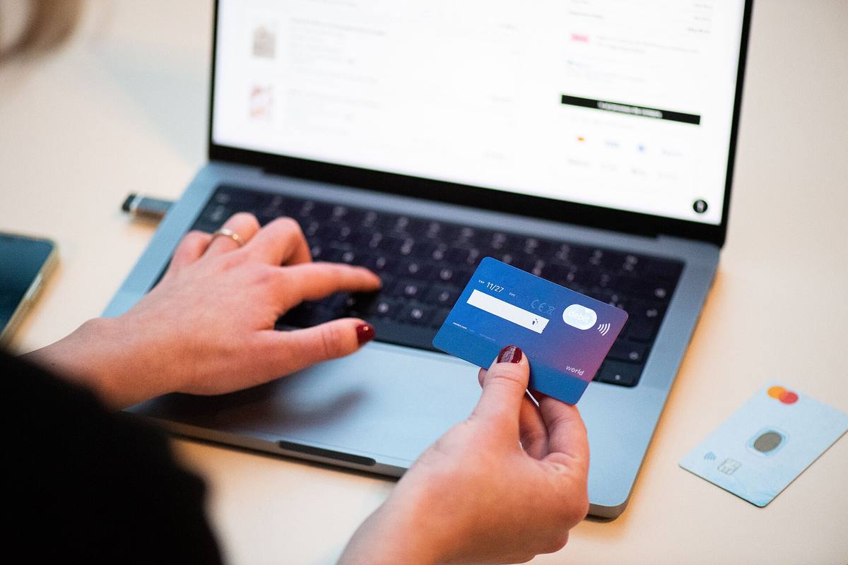 Nakupování v e-shopu na notebooku, v ruce platební karta