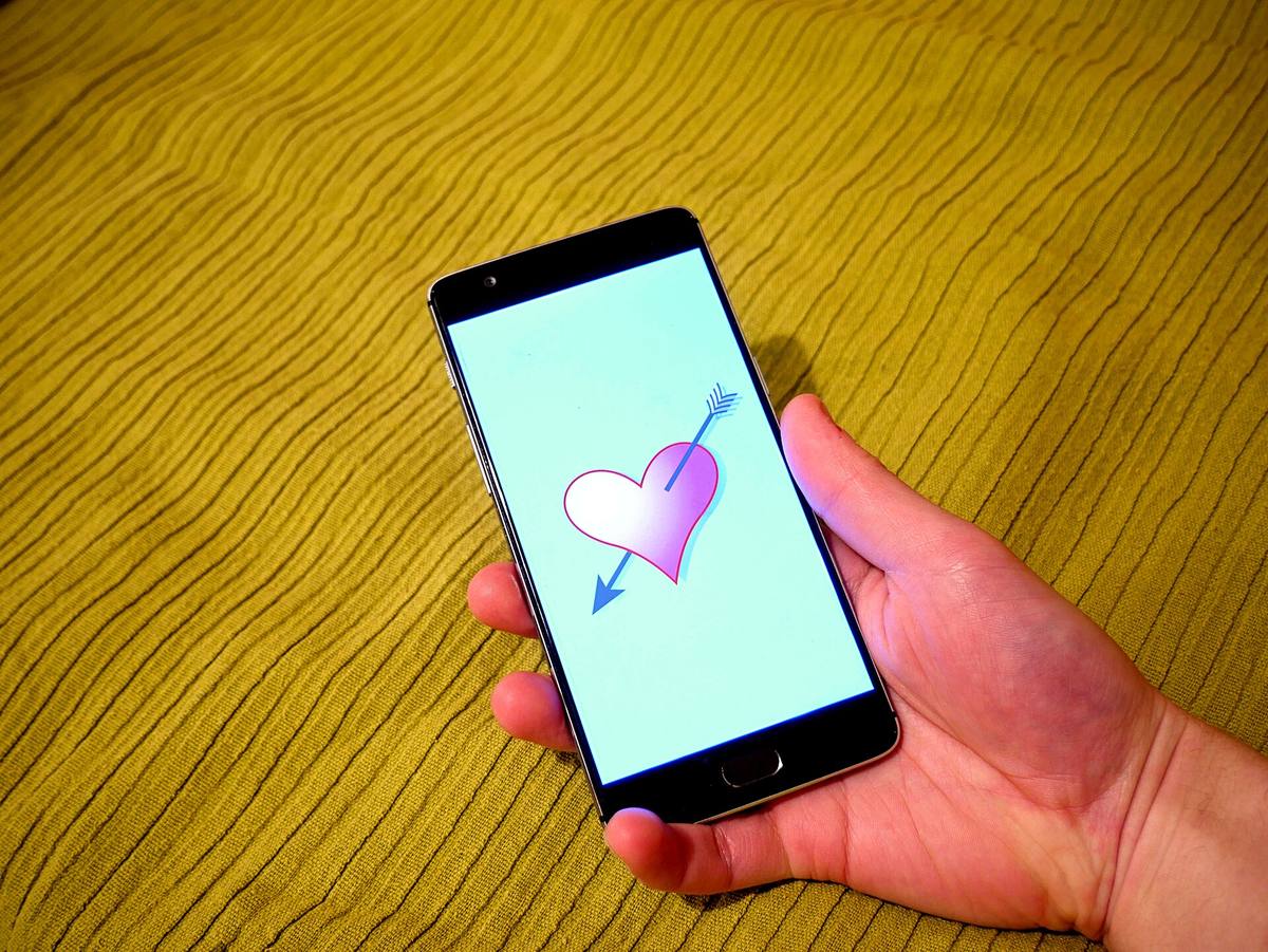 Ruka drží telefon s otevřenou seznamovací aplikací