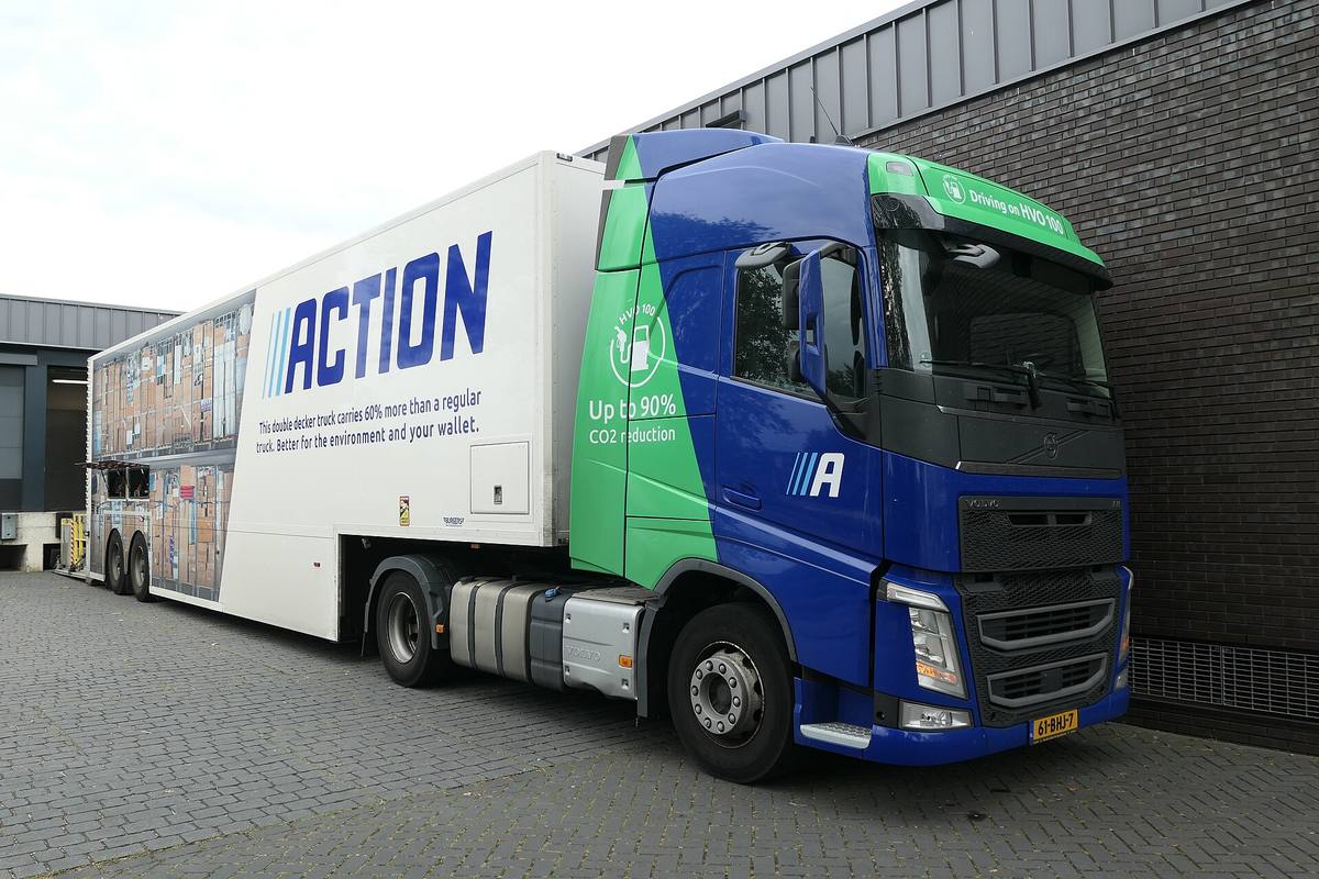 Modrozelený tahač Volvo FH s dvoupatrovým návěsem u skladu
