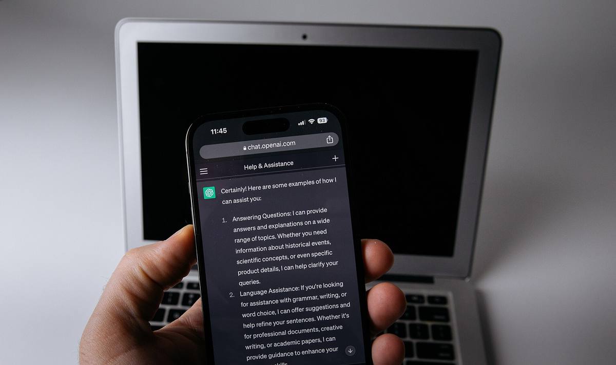 Telefon s aplikací ChatGPT položený u notebooku