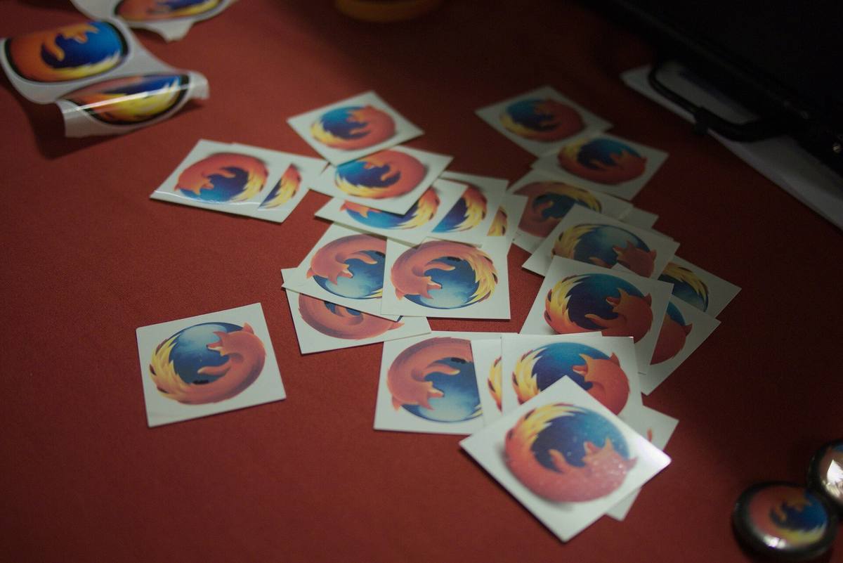 Čtvercové nálepky s logem Firefoxu rozházené na červeném ubruse