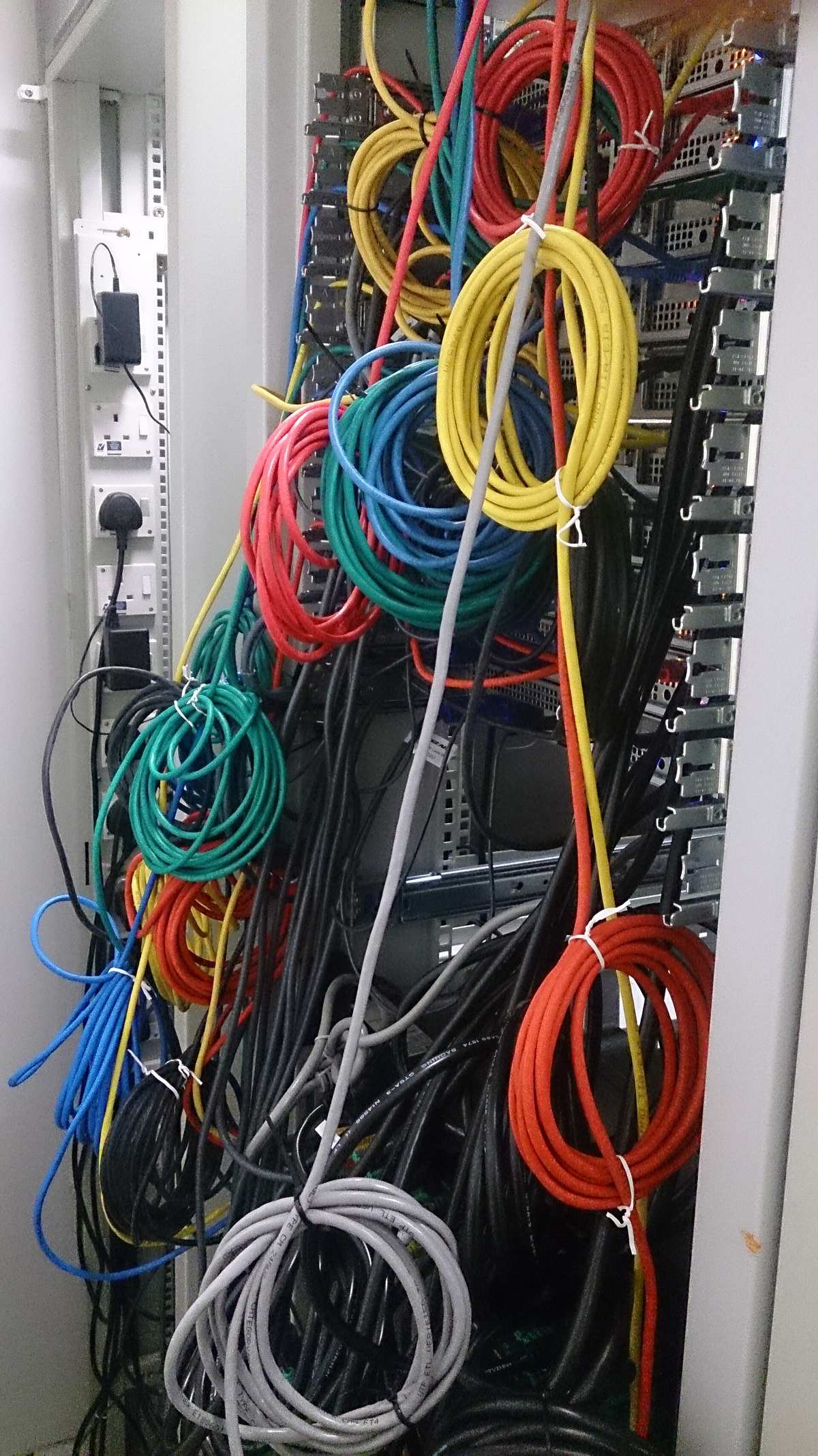 Svazky barevných síťových kabelů vedoucí do racku v serverovně